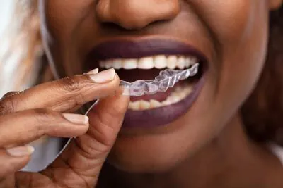woman using her clear aligners from Mitten Family Dental