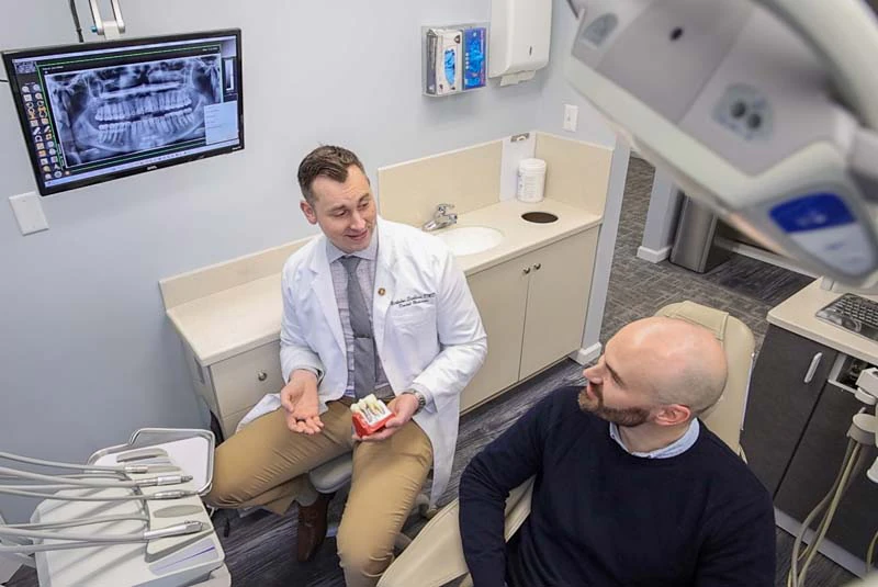 Nick Stebbins, DMD smiling at a male patient in the exam room atat Mitten Family Dental in Ionia MI.