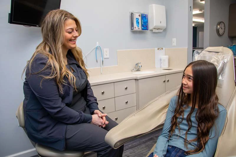 woman using her clear aligners from Mitten Family Dental