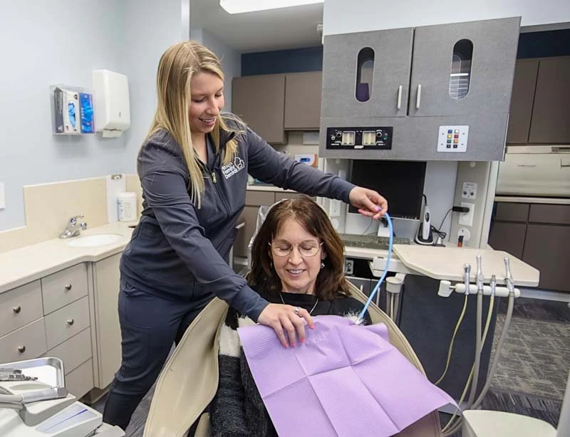 Female patient smiling at a staff member in the dental operatory at Mitten Family Dental